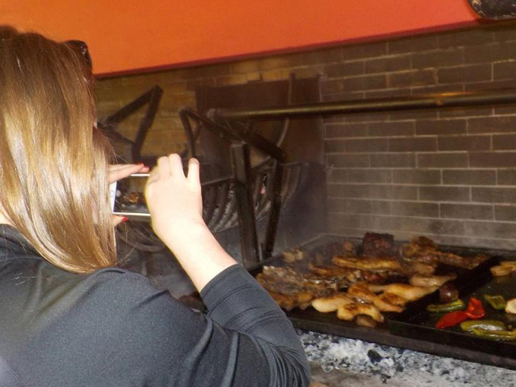 girl taking photo of an asado at estancia in argentina