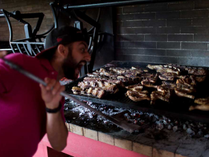 man taking a selfie next to an asado at estancia argentina